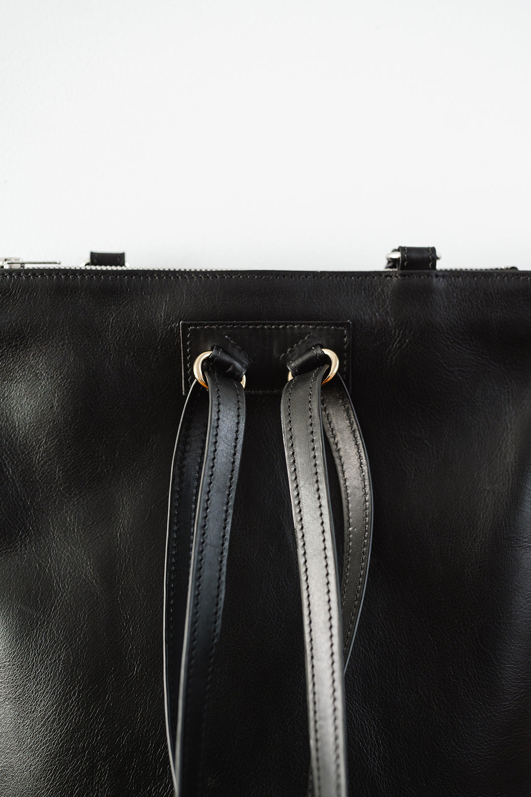 Close-up of The Backpack by Ella Jackson Australia – leather strap and gold hardware detail, minimalist black leather finish.
