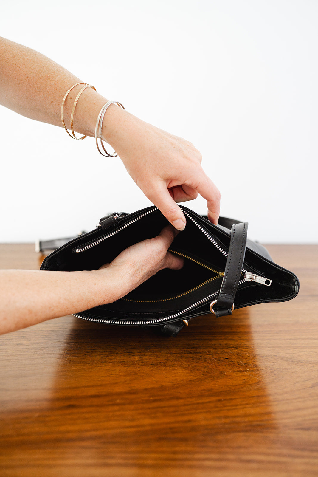 Hand opening The Backpack by Ella Jackson Australia – showing interior lined compartment with gold zip detail.