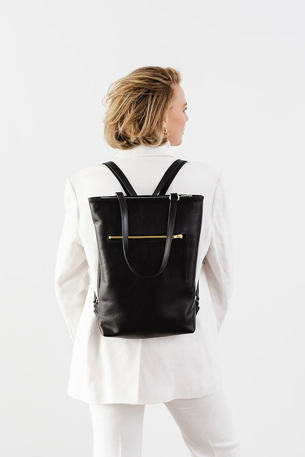 Woman wearing The Backpack by Ella Jackson Australia – rear view of minimalist black leather backpack paired with a white suit.