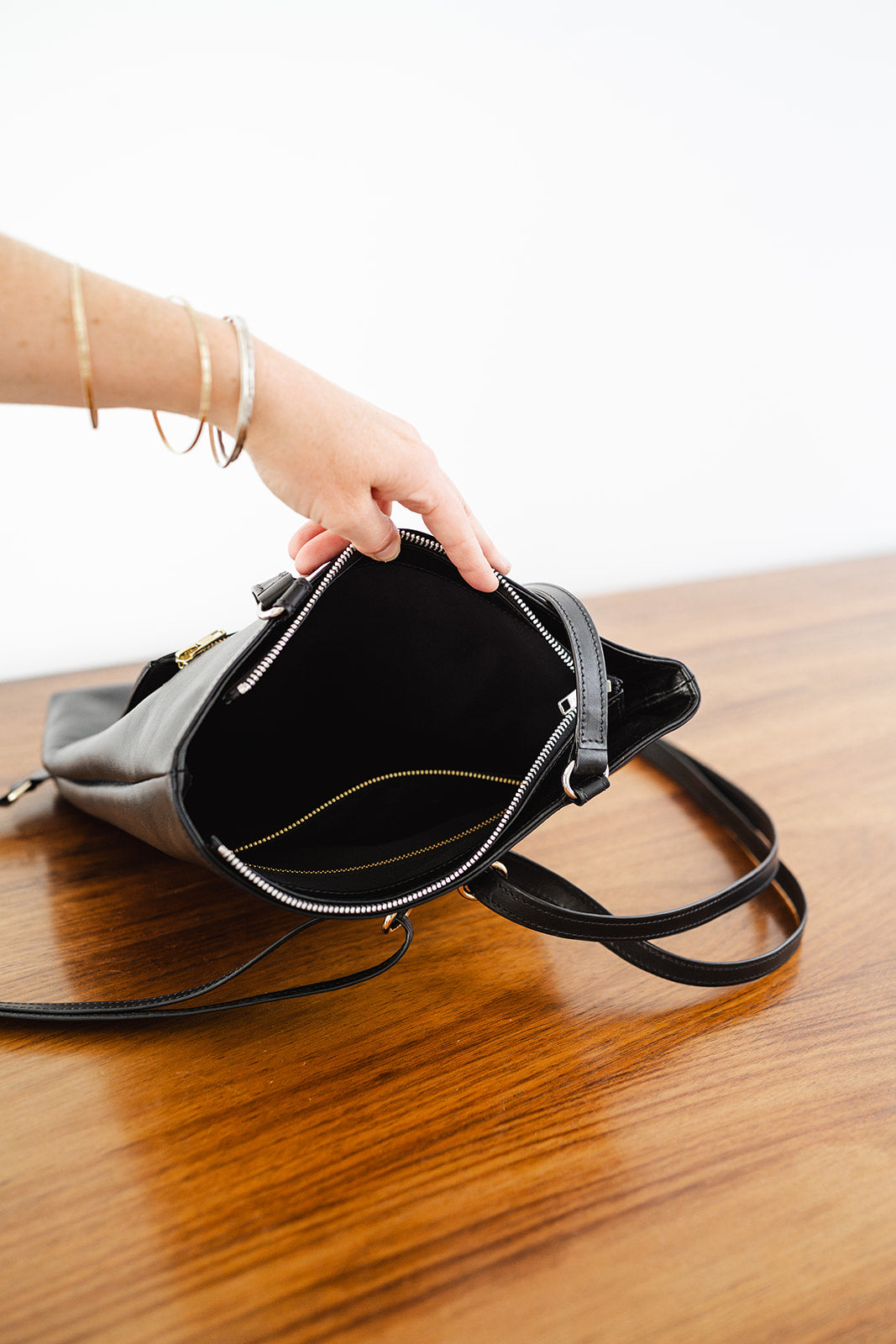 Hand revealing interior of The Backpack by Ella Jackson Australia – spacious main compartment with minimalist black lining.