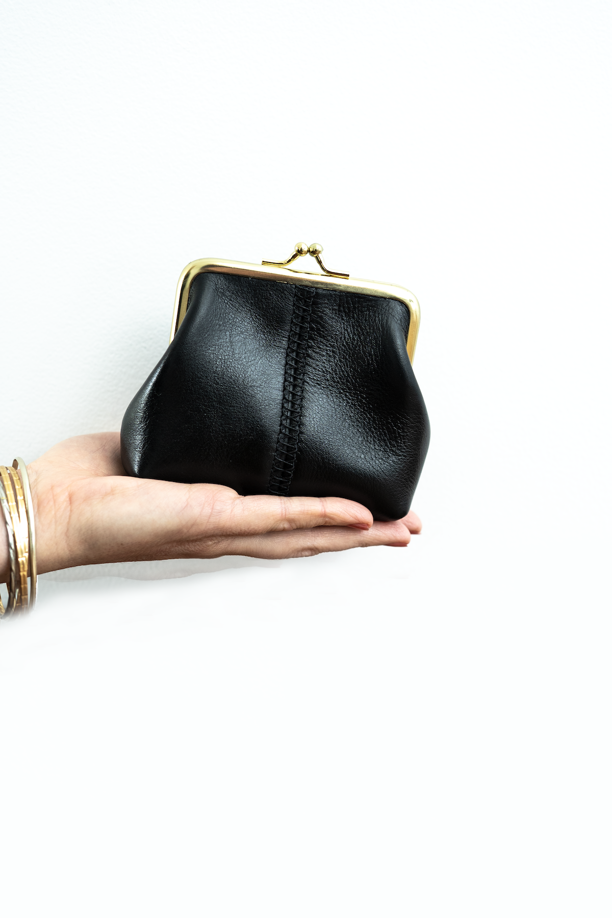 The Frame Purse by Ella Jackson Australia — front view held in hand, showcasing central stitch and gold clasp