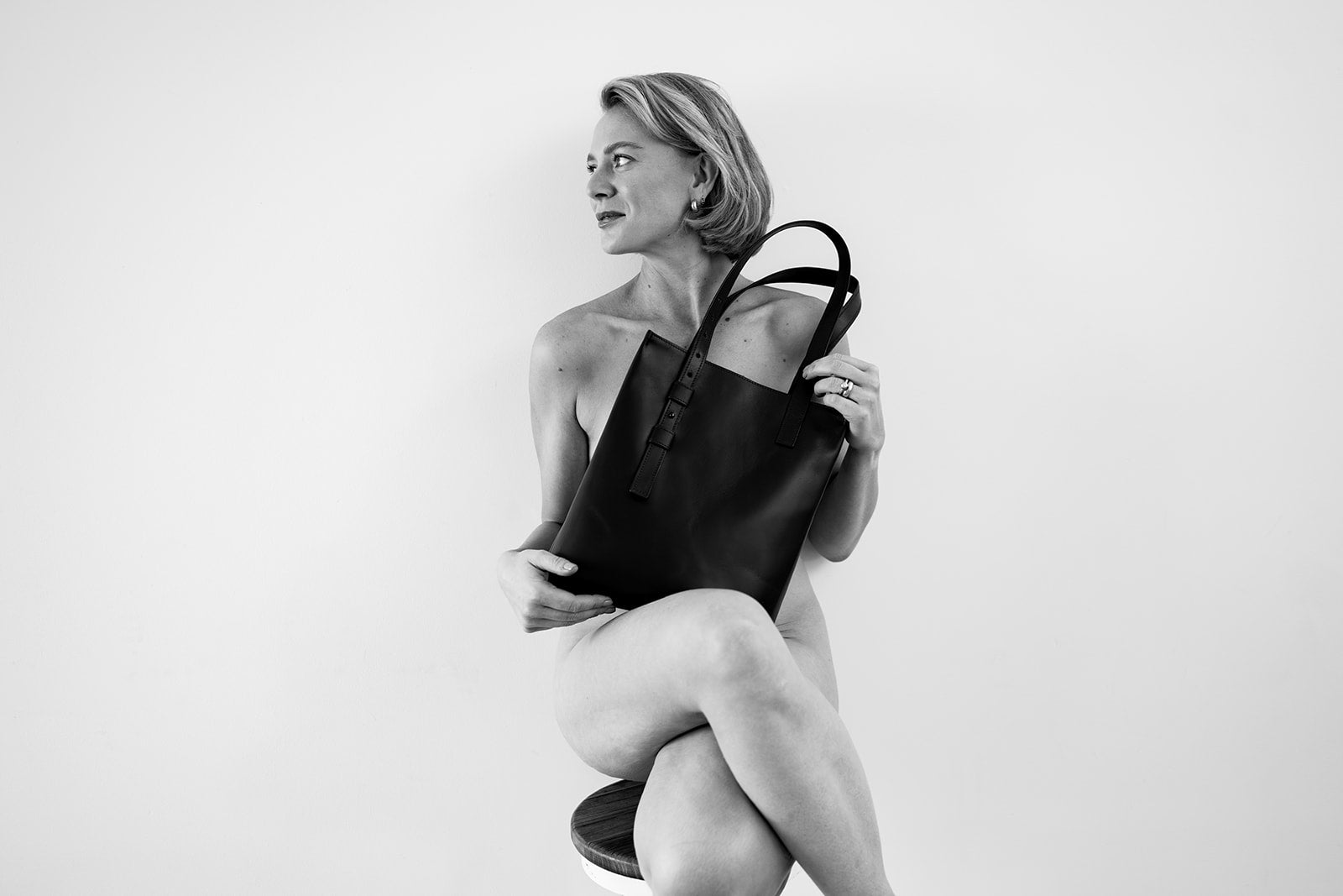 Woman seated holding The Shopper leather bag by Ella Jackson Australia – minimalist black and white portrait.