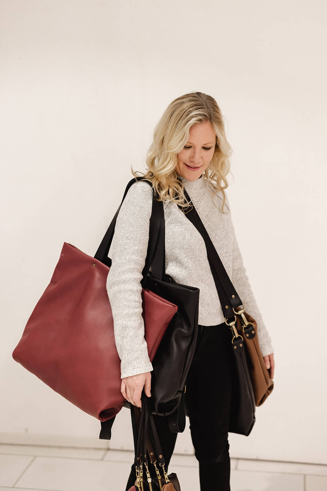 Ella jackson carrying multiple leather bags looking away from the camera- Tasmanian Leather Handbags