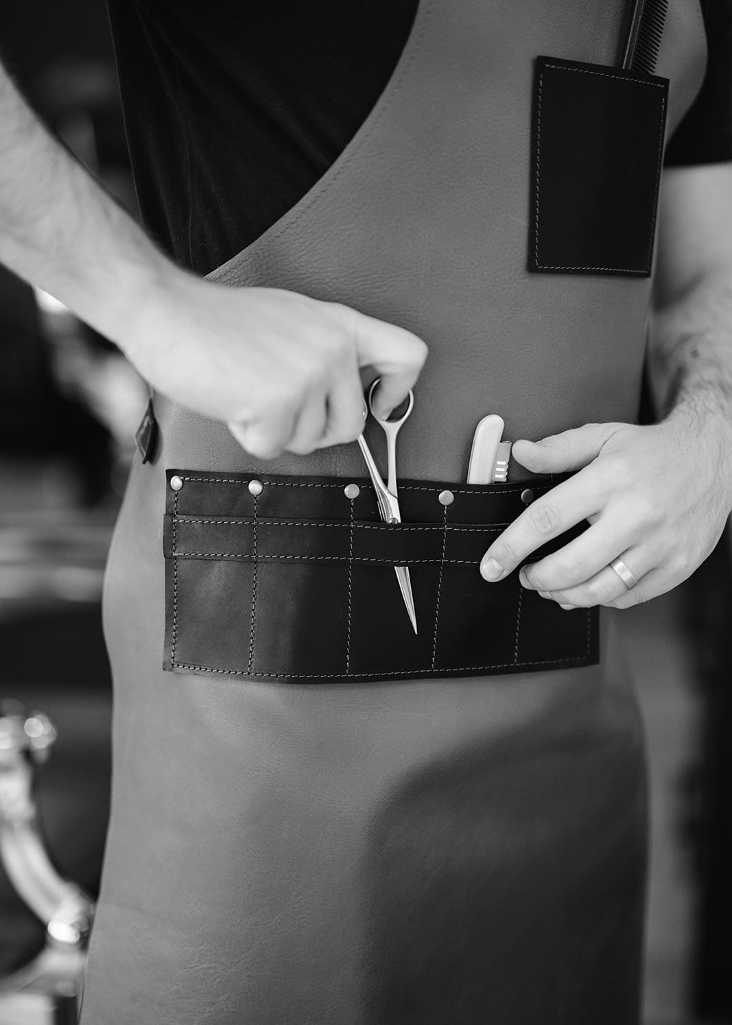 Close-up of a handcrafted leather apron, featuring a detailed tool pocket with scissors and a utility knife neatly placed inside