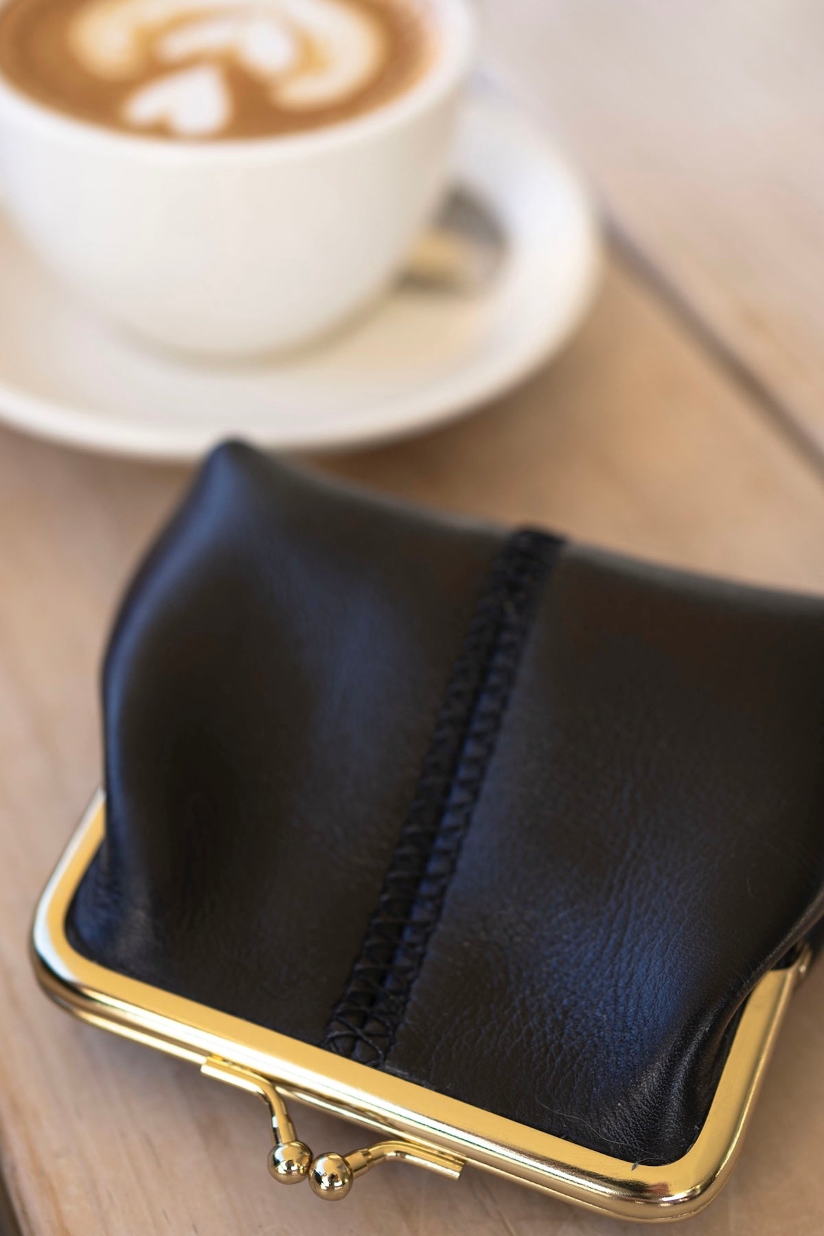 The Frame Purse by Ella Jackson Australia — close-up with coffee in background, showcasing gold clasp and central stitch