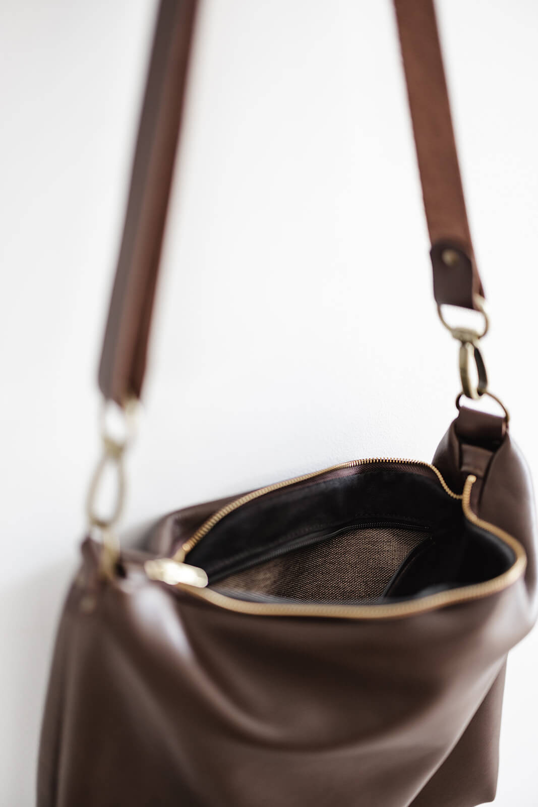 Product pic of the Ella Jackson Leather Carryall in Chocolate Brown. Pic is showing brown leather bag and strap, antique hardware, gold zip, black lining and brown internal pocket fabric