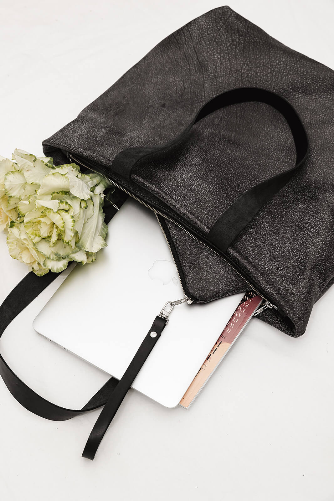 Product shot of the Ella Jackson Two-tone Grey Leather Backpack & Tote on a white background. Coming out of the bag is a bunch of cream and green flowers, an apple laptop, a magazine and a grey clutch with black wrist strap