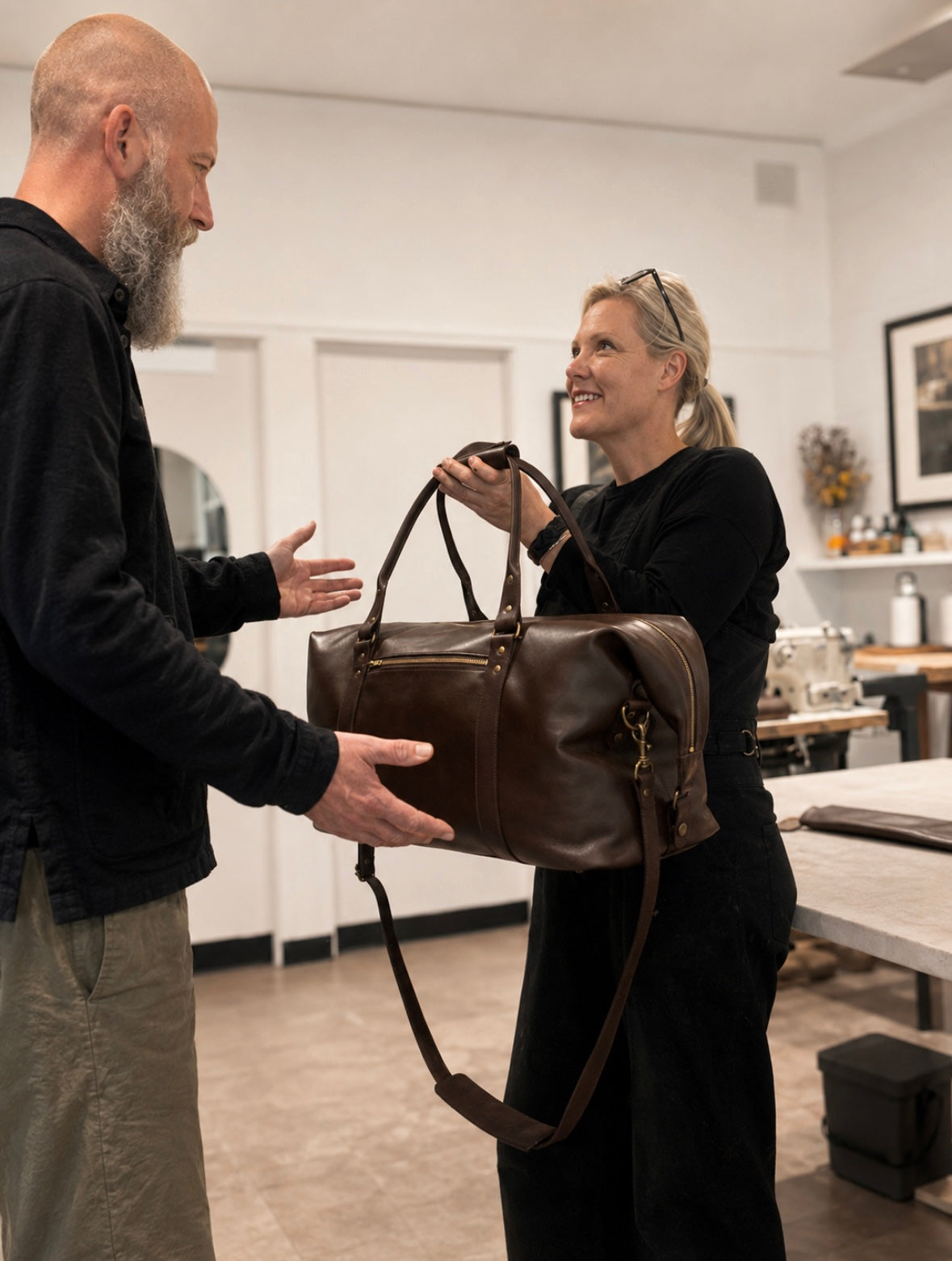 Ella Jackson presenting a completed custom leather weekender bag to its owner at STUDIO Ella Jackson, Hobart.